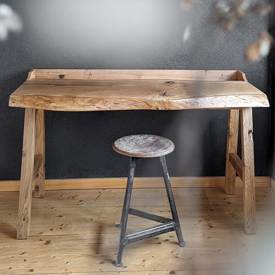 Schreibtisch aus massiver Eiche mit geschwungener Baumkante und einer praktischen Beilade als Wandanschluss handwerklich gefertigt von der Schreinerei Liebwerk von Salem am Bodensee.