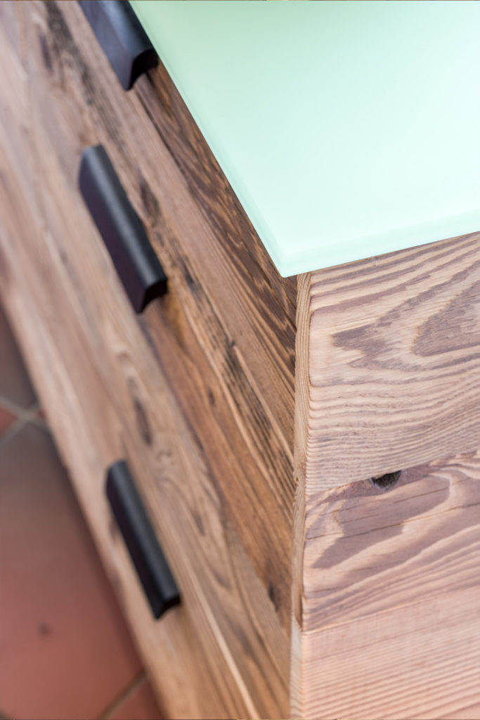 In der Schreinerküche von Liebwerk sind das Altholz und die grüne Glasplatte eine starke Kombination.