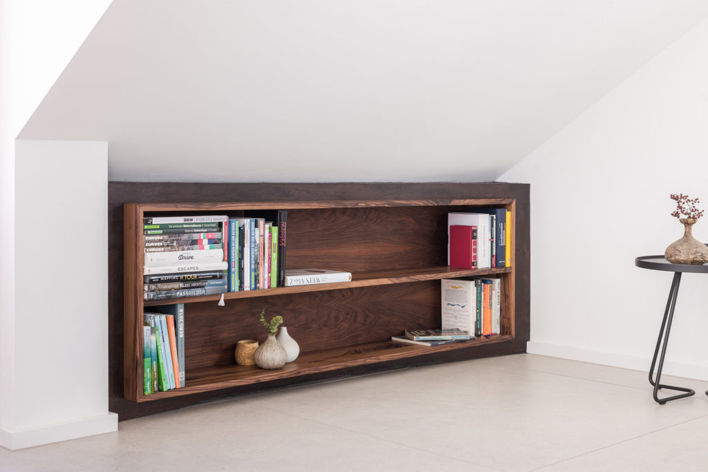 Ein Buchregal aus Nussbaum Massivholz eingebaut in einen Kniestock - top Job von Schreinerei Liebwerk.